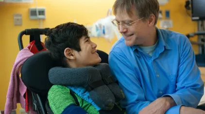 Young boy in a wheelchair by adults side