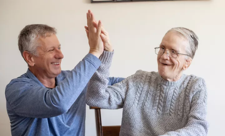 Two individuals smiling together, and giving a high-five