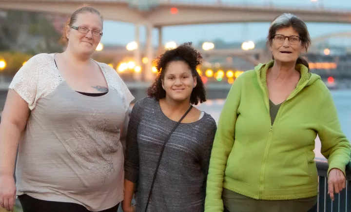 Individuals standing together and smiling by a lake walk
